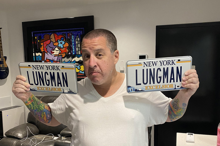 Dr. Noah Greenspan holding his "Lungman" NY license plates in his NYC offices of his Pulmonary Wellness Foundation