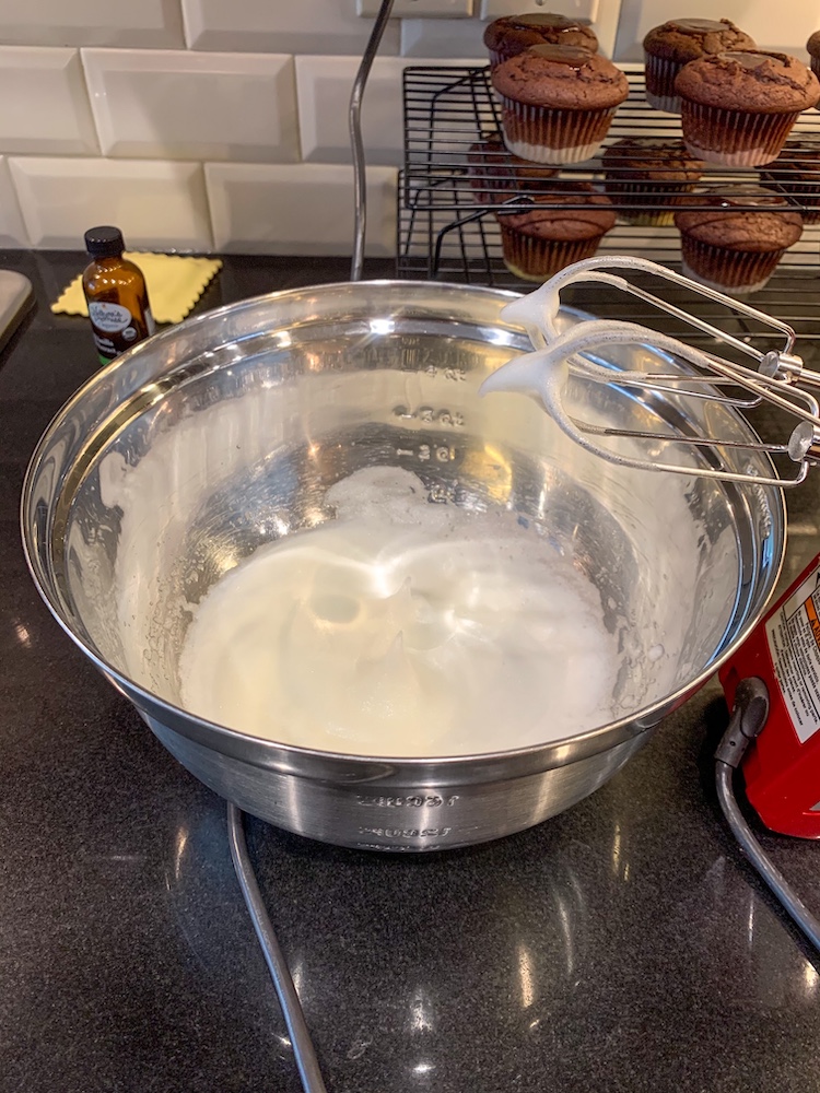 S’more cupcake recipe whipping egg whites in a bowl with hand mixer