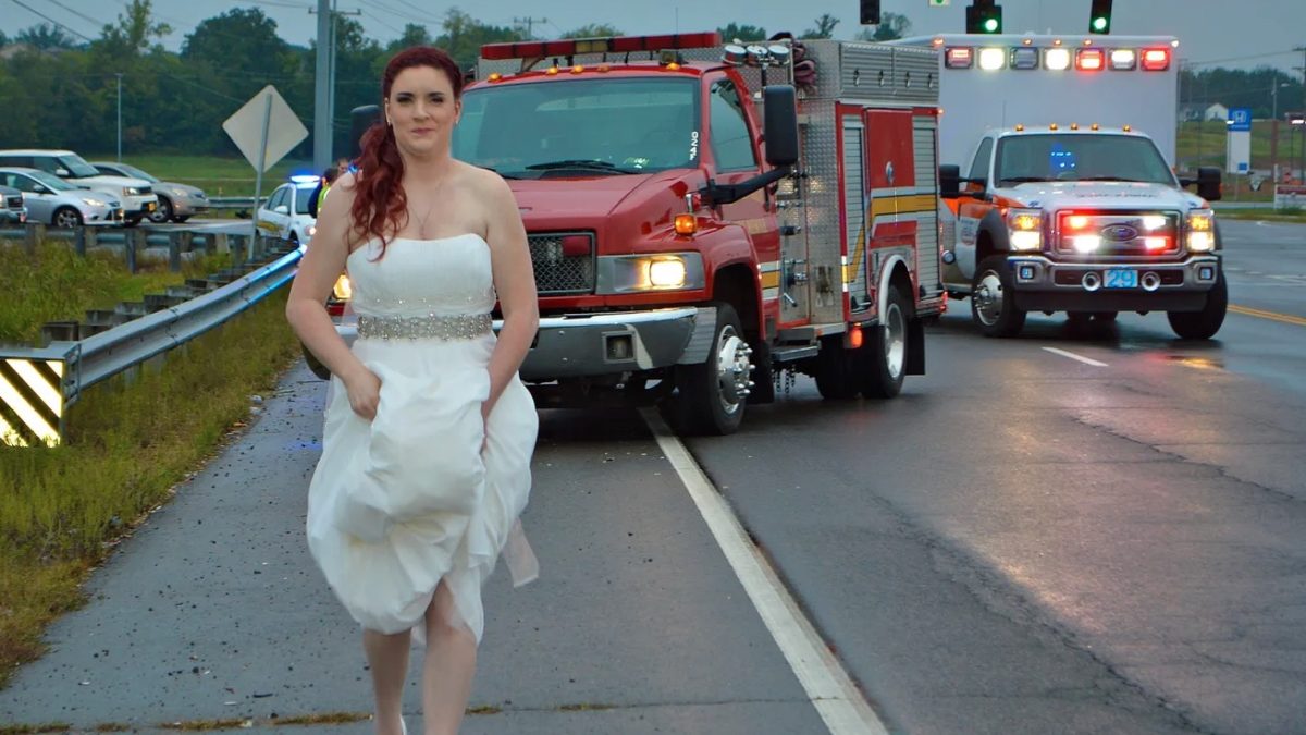 Bride Stuns in Wedding Dress While Aiding Crash Victims on Her Way to Her Reception | You may have already seen this photo of a bride in her wedding dress and shoes with her hair and makeup done and an ambulance and fire truck behind her.